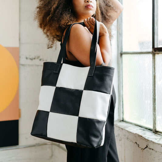 Model holding vegan leather checker tote bag. 